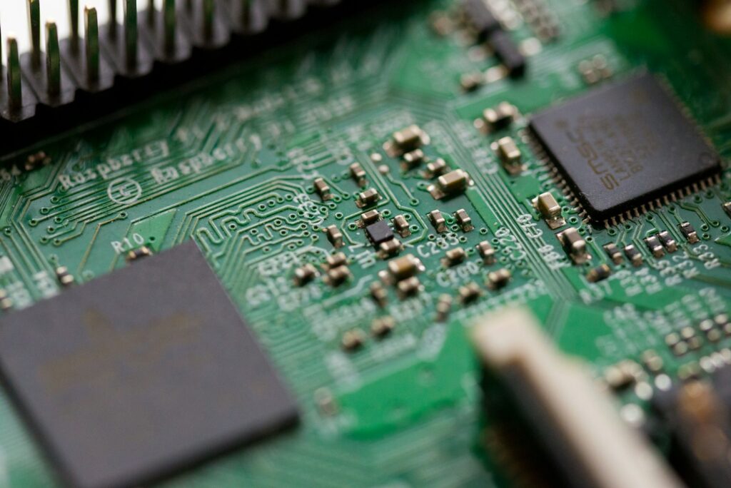 Placa-mãe verde de computador fotografada com efeito tilt-shift, destacando componentes eletrônicos