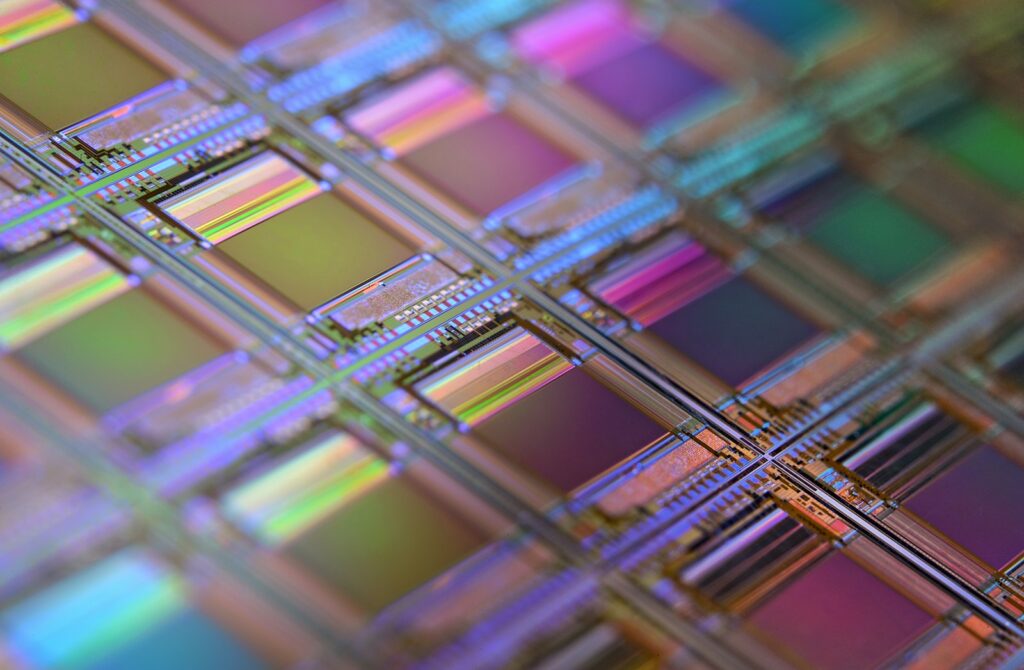 Wafer de silício com chips em macrofotografia, representando a fabricação de semicondutores