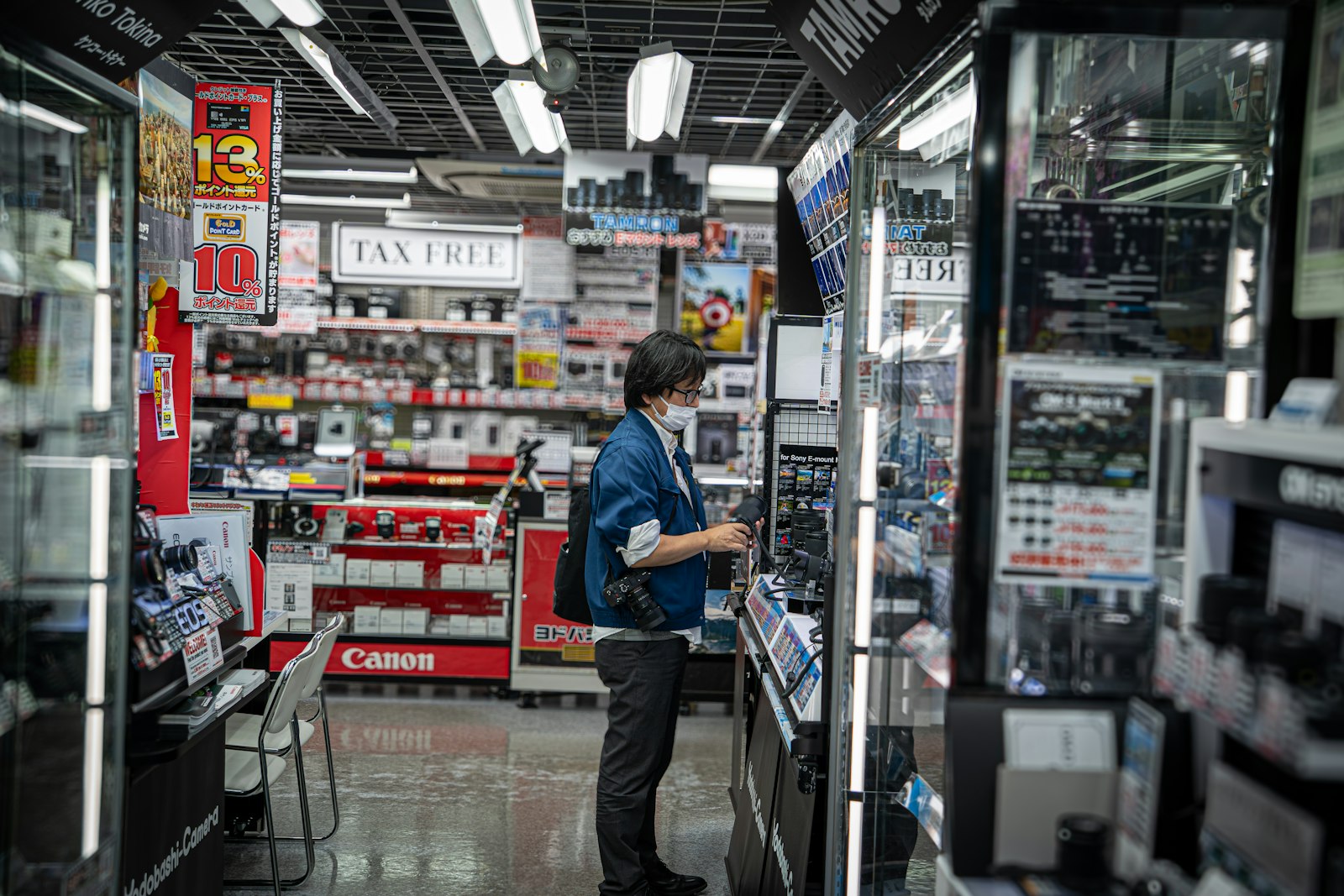 Pessoa observando prateleiras de produtos eletrônicos em uma loja iluminada