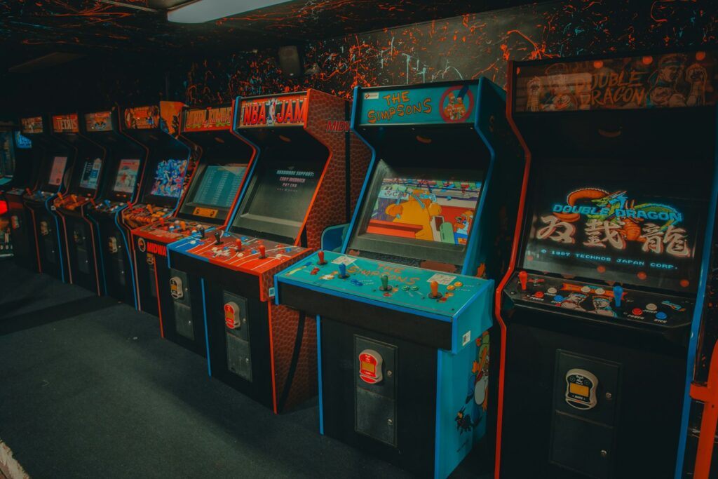 Fileira de gabinetes de fliperama vintage em ambiente escuro com luzes neon