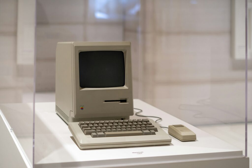 Computador Macintosh vintage com teclado e mouse sobre uma mesa