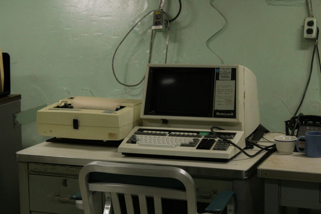 Computador pessoal vintage com monitor e impressora matricial sobre uma mesa de escritório