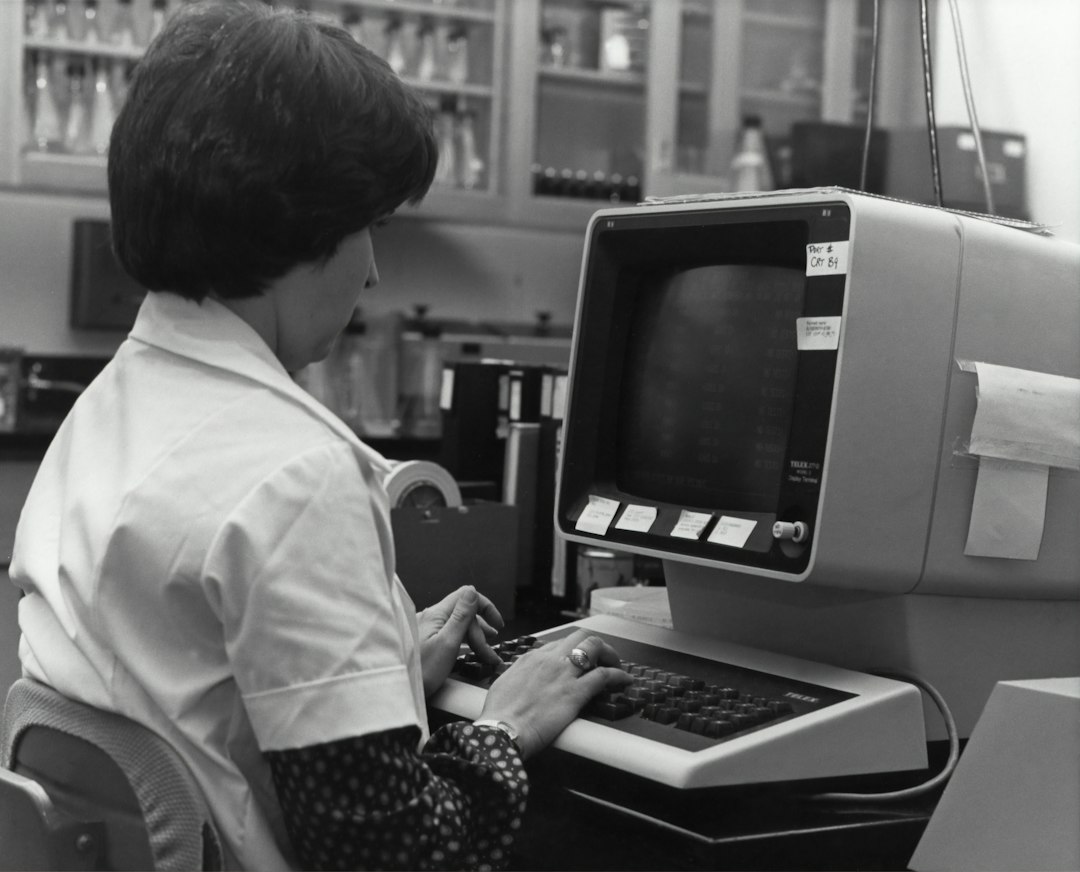 Mulher trabalhando com computador antigo, remetendo à história da programação